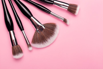 Wall Mural - Set of makeup brushes on pink background. Beauty artist, salon, professional services concept. Flat lay, top view. Copy space for your text.