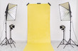 Empty studio with yellow backdrop and light equipment. Copy​ space​ for​ text or​ mock-up