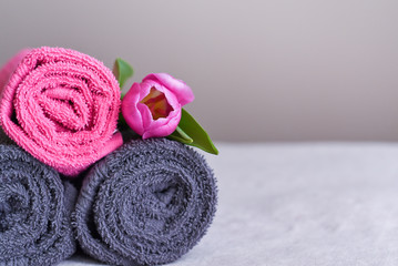 a stack of fresh towels in rolls with a pink flower, the concept of housekeeping and laundry at the hotel