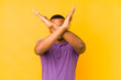 © Asier - Young latin man isolated on yellow background keeping two arms crossed, denial concept.