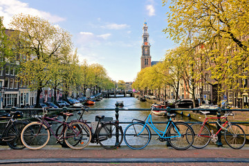 Sticker - Bicycles lining a bridge over the canals of Amsterdam with church in background. Late day light. Netherlands.