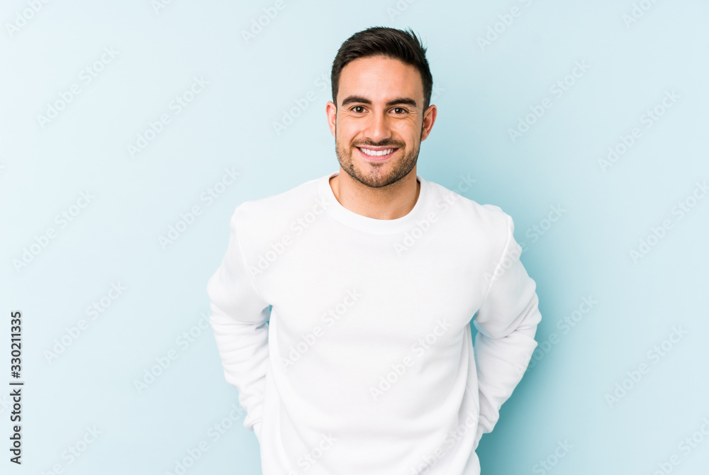 Young caucasian man isolated on blue background happy, smiling and cheerful. - obrazy, fototapety, plakaty 