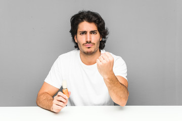 Wall Mural - Young man shaving his beard showing fist to camera, aggressive facial expression.