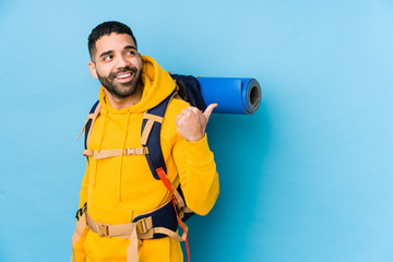 Wall Mural - Young arabian traveler backpacker man isolated points with thumb finger away, laughing and carefree.