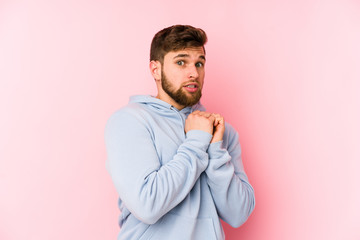 Wall Mural - Young caucasian man isolated on pink background scared and afraid.