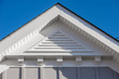 Close-up view of a white PVC triangle gable vent above a decorative trim board on a newly built American single family home