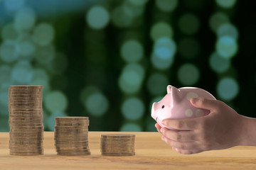 A piggy bank in the hands of a boy, And coins that were laid on the wood floor, savings concept