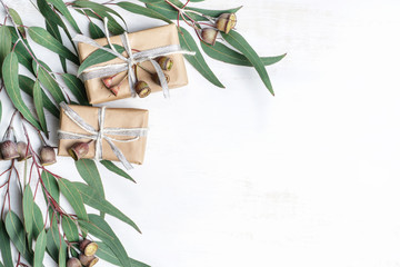 gifts wrapped in natural paper with silver ribbon & rustic twine surrounded by eucalyptus leaves & g