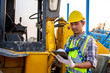 © tong2530 - Driving worker heavy wheeled tractor, Workers drive orders through the iPad, Wheel loader Excavator with backhoe unloading sand works in construction site.