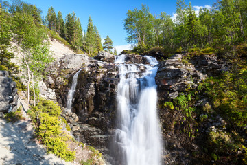 Wall Mural - One of beautiful waterfalls in Khibiny mountains. Sunny day with blue sky. The Kola peninsula, Russia