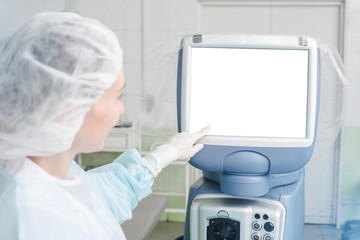 Mockup image, doctor working in operation room with special computer looking on display. Medical and technology concept