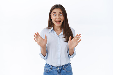 Wall Mural - Thrilled surprised girl react happy to exciting great news, shaking hands up gasping and looking astonished pleased camera with popped eyes and amused grin, stand white background