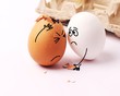 Two funny white eggs with faces drawn on them. Easter. Eggs with funny faces. Broken egg. My head hurts. Many problems. Pity, concern.