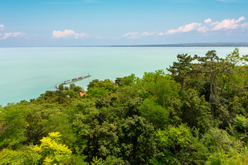 Poster - Lake Balaton with Tihany port and lots of green foliage in the foreground.