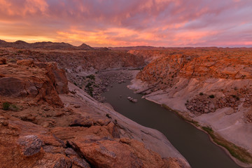 A beautiful pink sunset landscape view of the Augrabies Falls Gorge, mountains and river in South Africa, taken on a stormy cloudy golden evening.