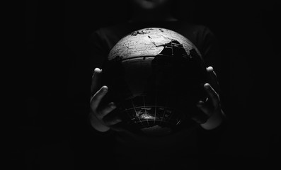 Wall Mural - hands of little girl hold globe sphere map isolated on black background. covid-19 pandemic infection