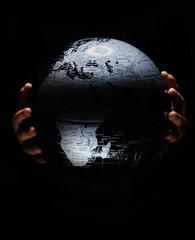 Wall Mural - hands of little girl hold globe sphere map isolated on black background. covid-19 pandemic infection