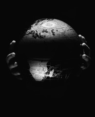 Wall Mural - hands of little girl hold globe sphere map isolated on black background. covid-19 pandemic infection