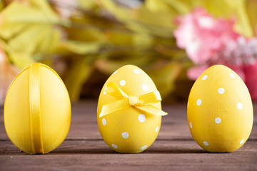 Easter holiday card. Three eggs painted in yellow with white spots decorated with a yellow bow. Selective focus. Copy space for text.