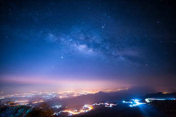 night sky with milky way and stars. night road illuminated by car. light trails