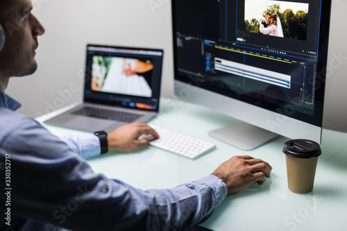 Fotografía Young man video editor with works with footage on his personal computer with big