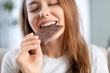 Leinwandbild Motiv Woman biting a chocolate bar