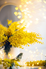 Bouquet of yellow mimosa flowers with bright gold interior decor with light spots