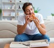 © Elnur - Man eating pizza having a takeaway at home relaxing resting