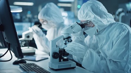 Wall Mural - Research Factory Cleanroom: Engineers / Scientists wearing Coveralls and Gloves Use Microscopes to Inspect Motherboard Microprocessor Components, Developing High Tech Modern Electronics