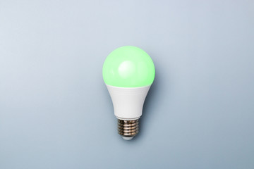 Wall Mural - switched on led bulb with green light on grey background with copy space for advert. business idea concept