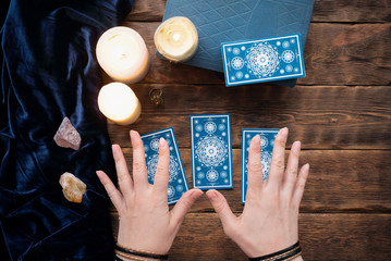 Wall Mural - Fortune teller with tarot cards in the hand on brown table background.