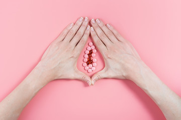 abstract image of female genital organs from hands and pills. concept of women's health and the treatment of female diseases of the urinary tract