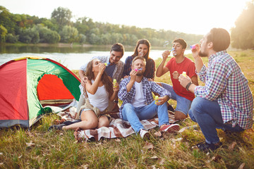 Wall Mural - Young people make soap bubbles while sitting on the grass on in nature.