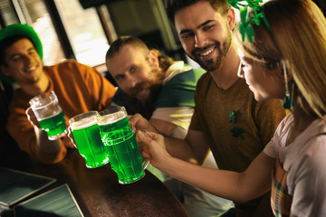 Sticker - Group of friends toasting with green beer in pub. St. Patrick's Day celebration