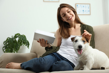 Canvas Print - Young woman reading book and her cute Jack Russell Terrier on sofa at home. Lovely pet