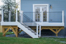 View Of A Classic Backyard Wooden Deck With Black Metal Balustrades Railing And White Columns On An American Single Family Home