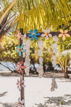 Vertical Shot Of Seashell Decorations And Flowers Hanging Under The Trees