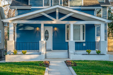 Beautiful Renovated Craftsman Style Covered Porch With White Columns, Beams,  Black Baluster Railing In Front Of A Blue Horizontal Vinyl Lap Siding Single Family Home In The East Coast USA