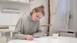 © stockbakers - Young Woman Thinking and Writing on Paper at Home