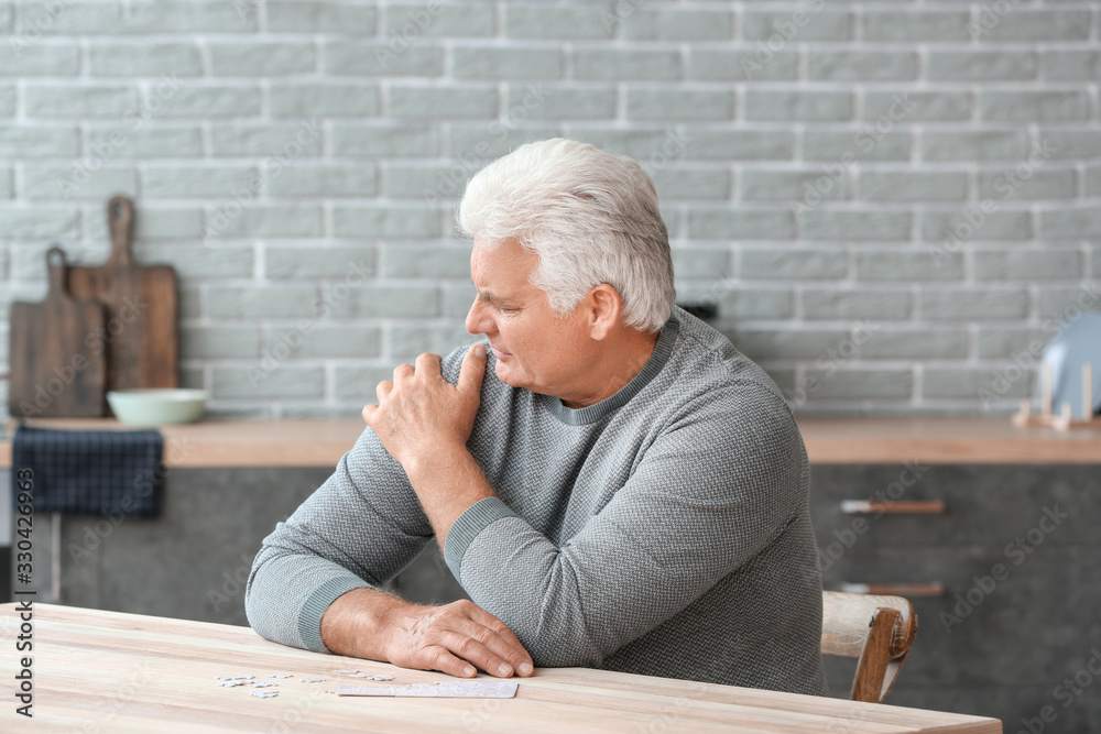 Senior man suffering from Parkinson syndrome at home