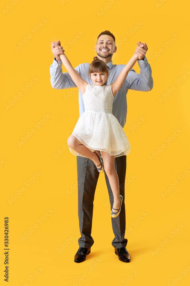 Father and his little daughter dancing against color background
