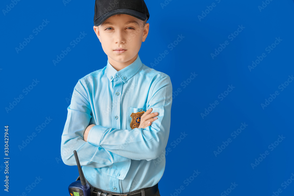 Cute little police officer on color background