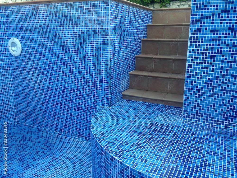 Mosaic tiles in the pool are blue and white. Ceramic tile. Construction ...