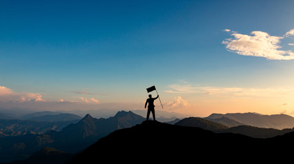 silhouette of businessman with flag on mountain top over sunset sky background, business, success, leadership and achievement concept.