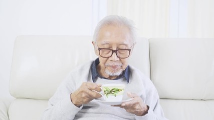 Wall Mural - Elderly man drinking a cup of hot tea on couch