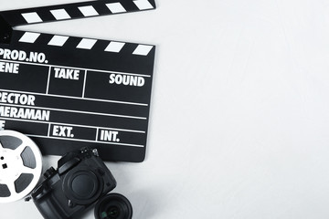 Wall Mural - movie clapper, modern camera and reel for video production on light table, flat lay. space for text