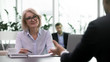 © fizkes - Smiling middle-aged businesswoman lead interview with male job candidate listening, happy senior female boss satisfied with man work applicant during hiring process, employment concept