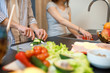 © Тарас Нагирняк - Close up photo, man cutting cucumber on cutting board, woman waching pepper, cooking time concept