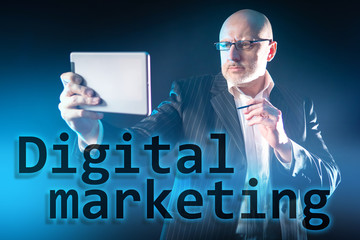 Poster - A man with a tablet and stylus in his hands on the background of the inscription Digital marketing. Promotion of goods and services using digital technologies. Internet marketing.