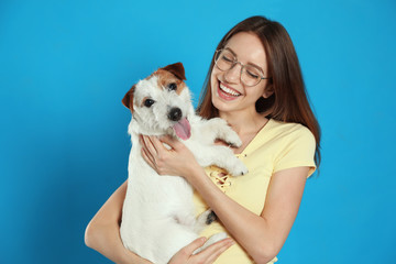 Wall Mural - Young woman with her cute Jack Russell Terrier on light blue background. Lovely pet